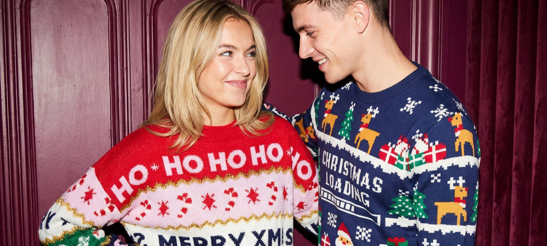 Smiling couple wearing festive Christmas sweaters with Ho Ho Ho, reindeer and Santa motifs